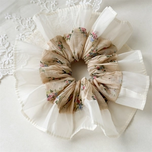Close-up of floral print scrunchie with cream chiffon ruffles on lace background