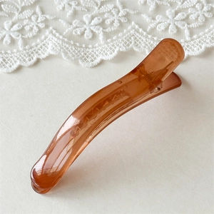 Close-up of translucent amber hair clip with sleek curved design and metal spring detail