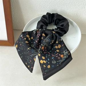Elegant black double-layer satin scrunchie with floral print ribbon on ceramic plate