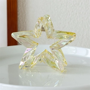 Close-up of star-shaped iridescent hair claw clip with laser hollow design on white tray