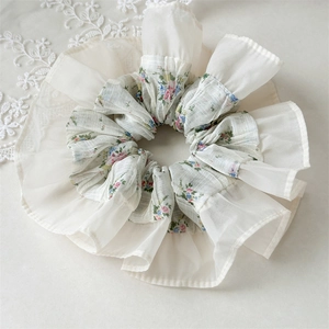 Detail of floral chiffon scrunchie featuring double-layered organza ruffles in cream white