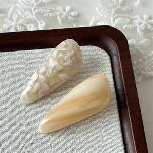 Close-up of two handmade acetate teardrop hair clips on a textured rustic background
