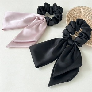 Close-up of pink and black satin bow scrunchies with smooth texture and soft pleats
