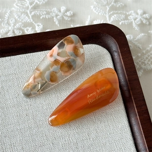 Close-up of marble pattern and amber acetate hair clips in a rustic wooden tray