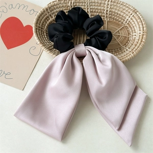 Detailed view of a soft pink satin bow scrunchie draped over a woven bamboo basket