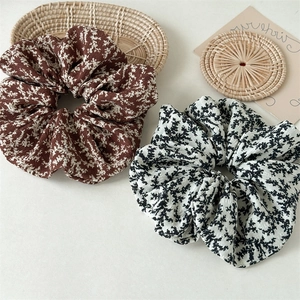 Detail view of two floral scrunchies with soft fabric textures on minimalist background