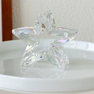 Macro shot of an iridescent star hair claw clip with silver spring on a tray
