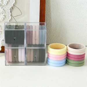 Détail d'élastiques à cheveux colorés dans une boîte de rangement en acrylique