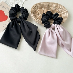 Close-up of satin silk scrunchies with long ribbons in black and lotus pink colors