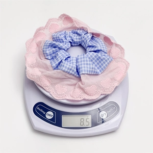 Detailed view of lightweight 8.5g blue plaid hair scrunchie with pink lace heart edges