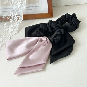 Detail of silk satin scrunchies with long ribbons in black and pink on lace fabric