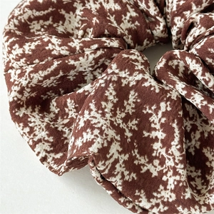 Elegant dark brown floral scrunchie with white patterns in a high-texture fabric
