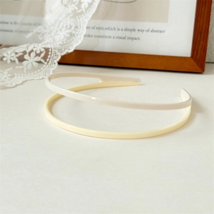 Close-up of cream and pale yellow double-layer acrylic headbands with smooth glossy finish