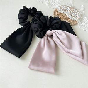 Close-up of black and pink satin scrunchies with long ribbons and smooth texture