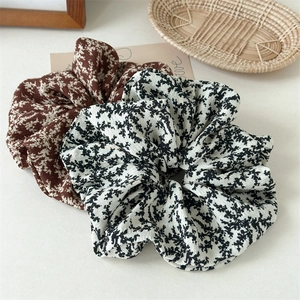 Detail of floral oversized scrunchies in brown and white chiffon on a minimalist background