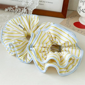 Detailed view of yellow striped fabric scrunchies with blue edges and handmade labels