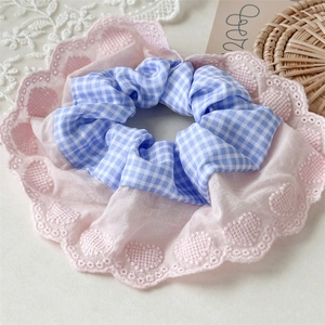 Macro shot of pink heart lace and blue plaid fabric detail on a large ruffled scrunchie