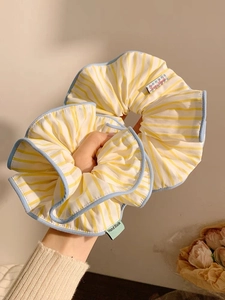 Detail of yellow and blue striped scrunchie with a hand-made label and soft fabric texture