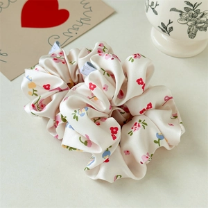 Detailopname van crème satijnen scrunchie met bloemenpatroon en zachte zijden textuur