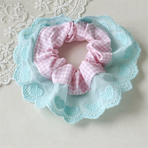 Close-up of pink checkered scrunchie with light blue lace and heart embroidery details