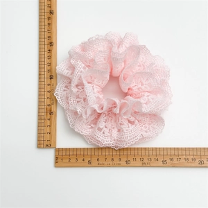 Détail d'un chouchou en dentelle rose avec une règle montrant le diamètre de 14 cm