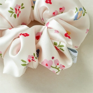 Detailopname van een satijnen scrunchie met bloemenpatroon en zijdezachte gladde textuur