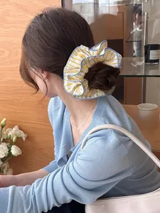 Detail of large yellow and blue striped scrunchie worn on a bun hair style