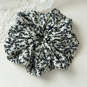 Detail of floral print scrunchie made of soft chiffon fabric with lace background