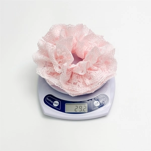 Chouchou en dentelle française rose pesant 29,2 grammes sur une balance blanche