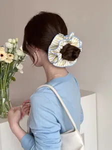 Detail of yellow blue striped scrunchie with layered pleats on female model hair