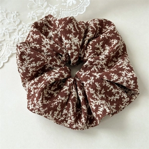 Detail of brown floral scrunchie with white botanical pattern and pleated fabric texture