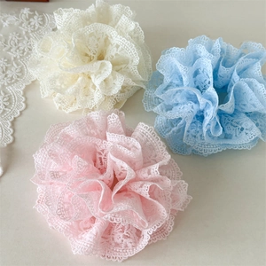Détail de trois chouchous en dentelle française en crème, bleu clair et rose doux