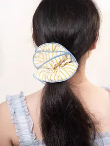 Detail showing oversized yellow and blue striped fabric scrunchie on a ponytail