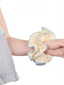 Detail of yellow and blue striped oversized fabric scrunchie worn on model wrist