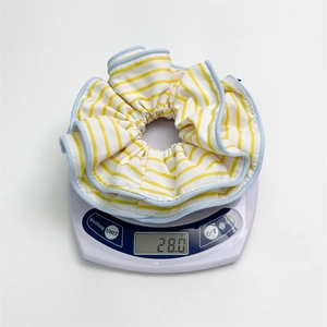 Striped yellow and blue fabric scrunchie being weighed at 28.0g on a digital scale
