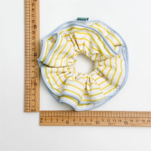 Detail of a large 15cm yellow striped fabric scrunchie with blue edging and handmade label