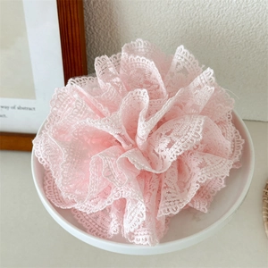 Détail de chouchou en dentelle française rose avec un design de fleur de crochet multicouche