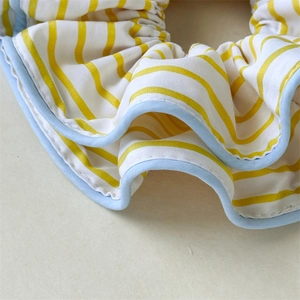 Detail of yellow and blue striped fabric scrunchie with soft cotton texture and fine stitching