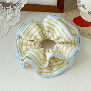 Detail of yellow and blue striped fabric scrunchie on a decorative aesthetic background