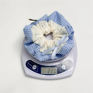Detailed view of lace scrunchie with blue checkers and pearl bow on a digital scale