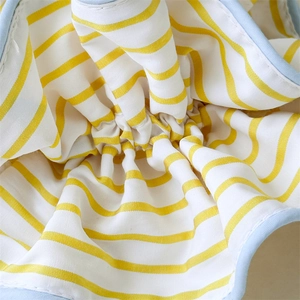 Macro shot of yellow and white striped fabric texture with light blue piping and pleats