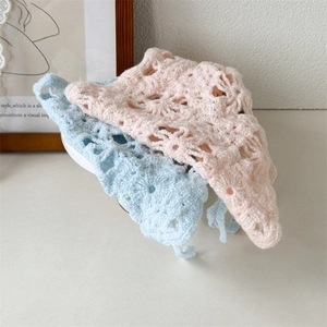 Detailed close-up of hollow crochet knit headscarf texture in soft blue and pink tones