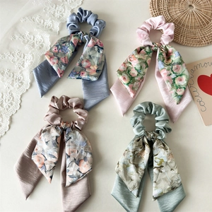Close-up of four-piece satin scrunchie set with floral ribbons in pastel vintage colors
