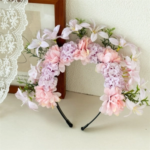Dettaglio del cerchietto floreale con fiori rosa e viola e foglie verdi realistiche