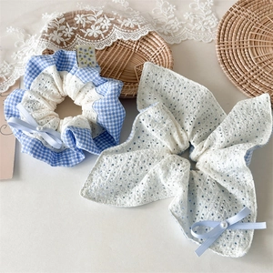 Close-up of blue plaid and white lace hair scrunchies with elegant bow and pearl detail