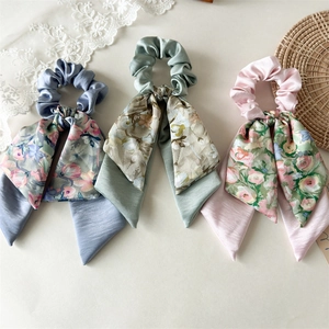 Detail view of floral bow hair scrunchies in dusty blue, sage green and soft pink colors