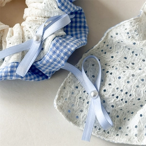 Detail of blue plaid fabric and white lace scrunchie with silk bow and pearl accent