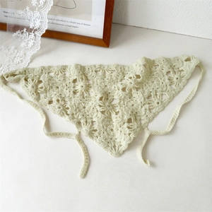Detail of light green crochet knit bandana with hollow floral pattern and side straps