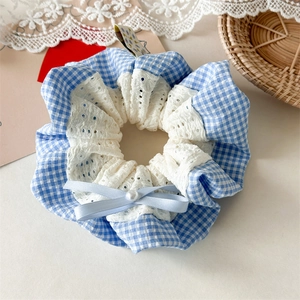Detailed close-up of blue plaid scrunchie with white lace, bow and faux pearl detail