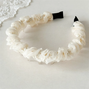 Detail view of cream pleated chiffon headband with white pearls and soft lace background